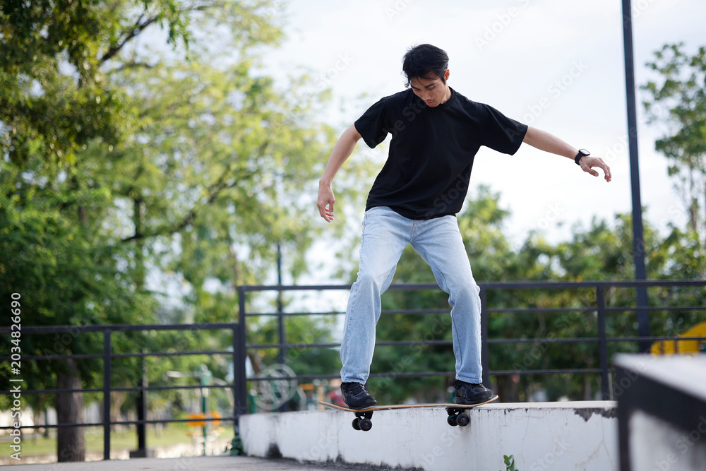 Obraz premium Young Asian Man Performing Skateboard Trick at Outdoor Skate Park