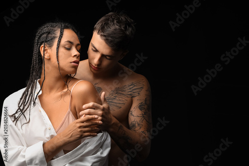 Young couple hugging on black background