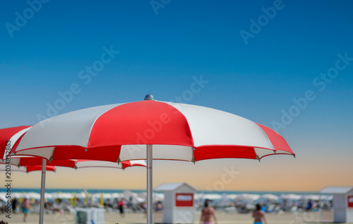 Geometric umbrellas create cool oases of shade on the hot sand by the crystal-clear sea.
