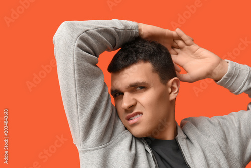 Schilderij op canvas Handsome young man feeling bad smell from armpits on orange background