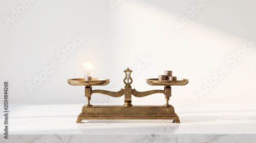 Vintage brass scale balancing a glowing lightbulb and coins