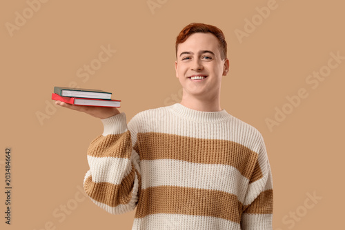 Young man holding books on ...