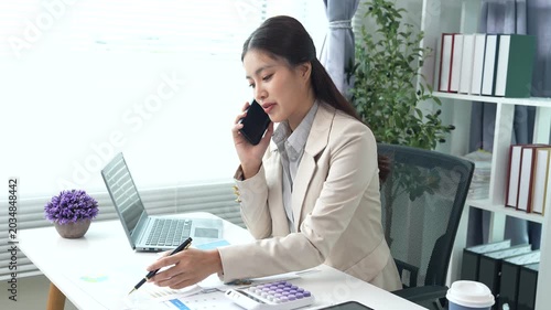 Young businesswoman reviewing financial documents and reports at a modern office desk, analyzing data and managing paperwork with focus and professionalism.