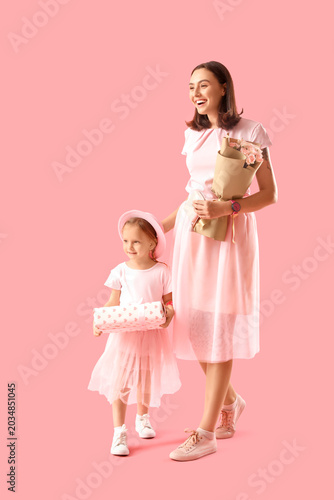 Cute little daughter greeting her beautiful mother with gift box and bouquet ...