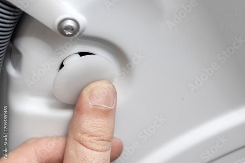 Plumber installing or removing washing machine transit shipping bolts. Man connecting water inlet and drain hose pipe. Plastic hole plugs, wrench tools. Home appliance installation concept.