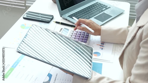 Business professional reviewing financial reports and performance charts at a modern office desk, analyzing data, planning strategy, and managing corporate documentation.