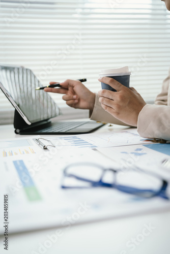 Business professional reviewing financial reports and performance charts at a modern office desk, analyzing data, planning strategy, and managing corporate documentation.