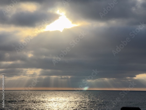 Foto A dramatic wide landscape view of spectacular crepuscular sun rays or god rays bursting downward through dark storm clouds over the sea in La Jolla, California