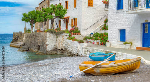 white house with colorful shutters of a seaside village with boats on the beach in Peloponnese Greece