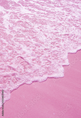 Surreal pop art style ocean waves splashing on pink colored sand beach