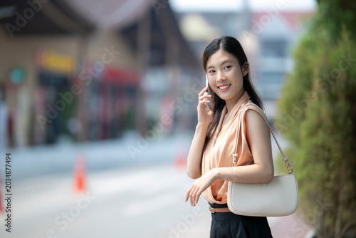 Bild auf Leinwand Young woman using smartphone on city street with modern buildings