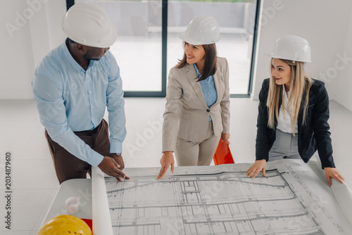 Obraz na plátně Project team collaborating on construction blueprints and planning