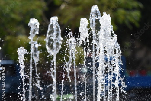 Water fountain sprays create a refreshing scene in an urban park during midday sunshine