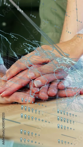 Vertical video: Hands stacking settling on wood table under blue overlay third hand joining support