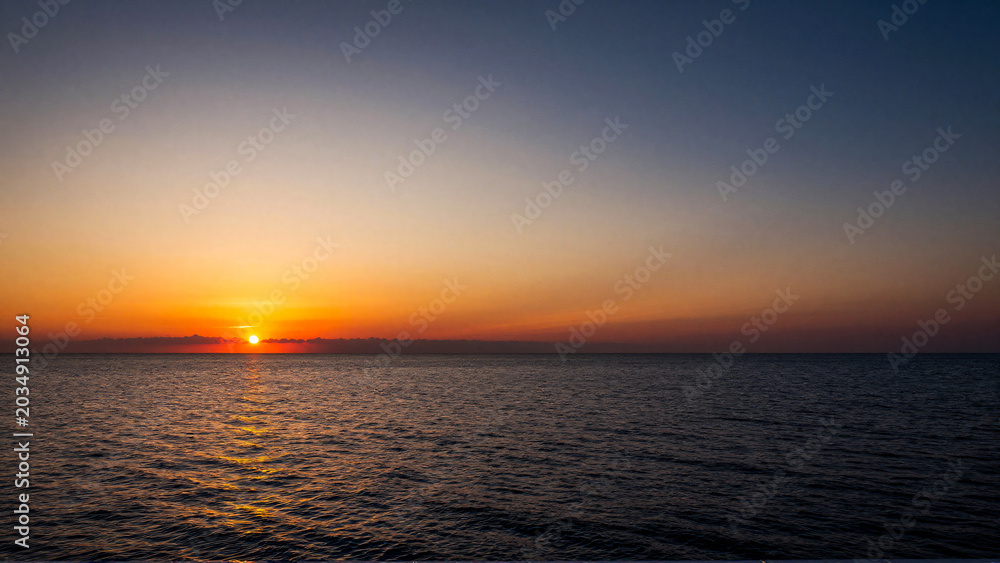 Obraz premium Tranquil Ocean Sunset with Radiant Golden Sky