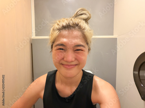 Foto Asian Thai woman with a strained smile on the toilet, experiencing constipation and difficulty with a bowel movement in a restroom