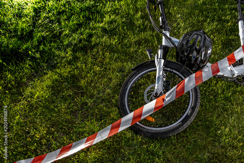 Bicycle crash scene with helmet and warning tape on grass