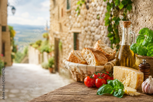 Italian food with bread, olive oil, parmesan cheese and tomatoes on wooden table. Italy cuisine and travel concept.