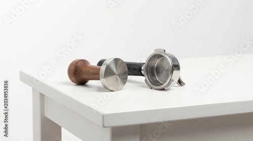 Coffee tamper and portafilter on table.