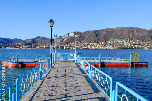 фотографія Blue pier extending into Lake Iseo with mountain views and crystal-clear water under a bright sky, capturing peaceful travel and summer atmosphere in northern Italy