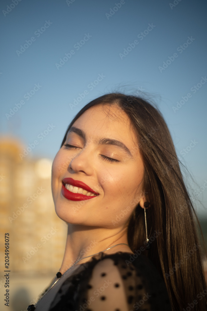Fototapeta premium Portrait of a young and sensual woman smiling on a building rooftop