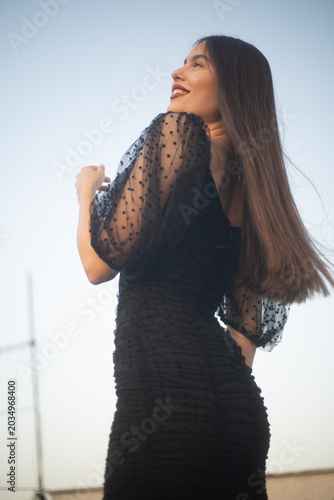 Beautiful and sensual young woman in a dress on a building rooftop in the golden hour