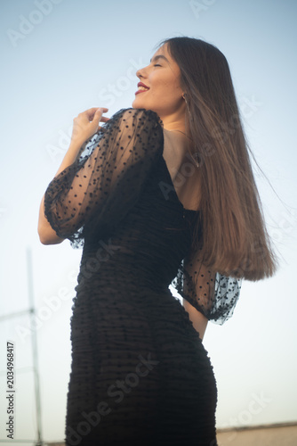 Beautiful and sensual young woman in a dress on a building rooftop in the golden hour