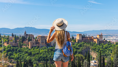 Woman with straw hat looking at the alhambra fortress in granada
