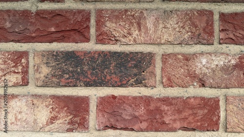 Red clinker brick wall background with dark burnt accent brick, rustic brickwork texture close up