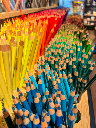 Rows of sharpened colored pencils standing upright, showing a vibrant gradient of colors from blue and green to yellow, orange, and red, representing creativity and extensive art supplies.