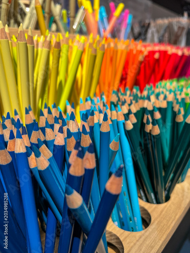 Groups of colored pencils organized by hue, showing a wide spectrum of colors from blue and green to yellow, orange, and red, ready for creative art projects - stock photo