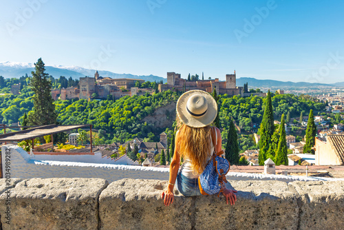 Photos young woman with leather backpack overlooking alhambra palace in granada spain,