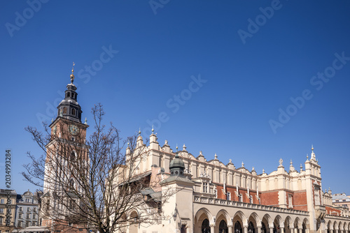 Historic market square in Krakow showing the Cloth Hall and town hall tower under a clear blue sky
