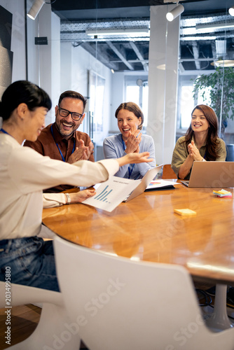 Business team applauding successful presentation in modern office meeting discussing achievement