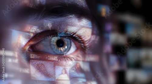 Close-up of human eye with digital screens and media projected on face representing data monitoring and information overload