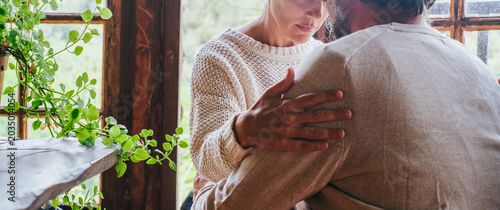 Canvastavla A tender moment between a couple sharing comfort and support by a rustic window, showing intimacy, emotional connection and caregiving in a cozy home setting with natural light and houseplants