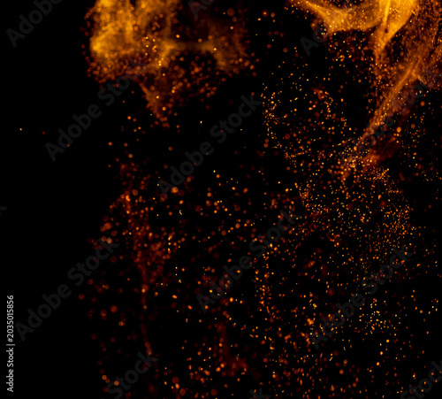 Golden particles swirl against a deep black void