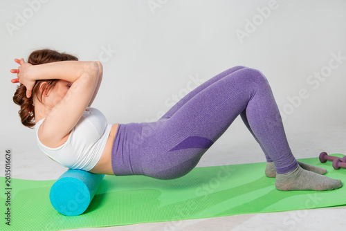 Full length portrait of young woman in sportswear doing abdominal exercise on yoga mat isolated on white background.