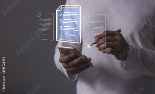 Young man with smartphone mobile hand using a pen touching to sign a Online Business Contract, Electronic signature, Contract signing, Digital documents, Future smart contract
