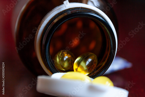 Pills spilling out of a bottle isolated on dark background, Vitamin for health