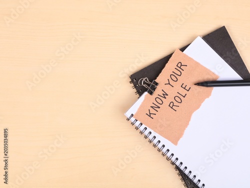 Know your role text handwritten on a piece of torn paper on book. Represents accountability, team management, business organization, and setting clear responsibilities in the workplace