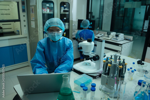 Bild auf Leinwand Asian team researchers examining natural water sample for contaminants and microplastics next to laboratory bottle