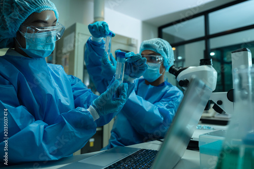 Fotografie Asian team researchers examining natural water sample for contaminants and microplastics next to laboratory bottle