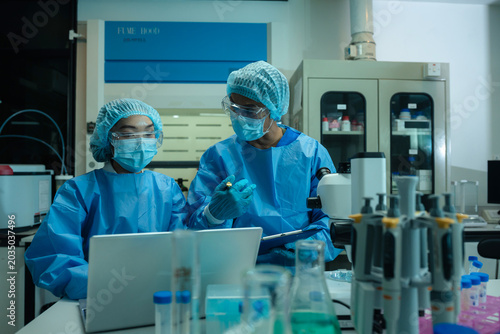 Medical or research scientist or doctor using looking at a test tube of clear solution in a lab or laboratory.