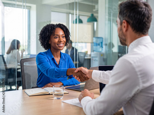 Konstfotografi Smiling African American businesswoman shaking hands with a male colleague