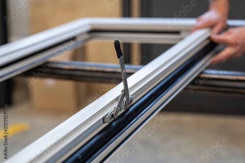Foto Détail d’un système d’ouverture intégré sur un châssis aluminium en cours d’assemblage dans un atelier de menuiserie spécialisée