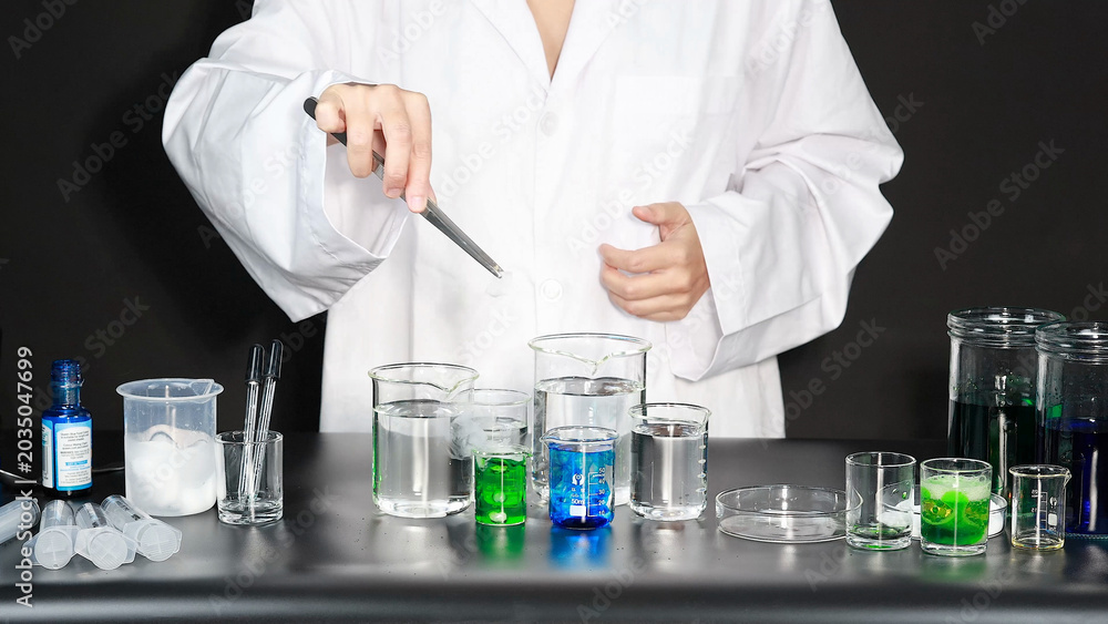 Fototapeta premium Scientist in White Lab Coat Using Tweezers to Conduct Chemistry Experiment