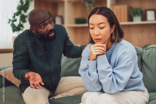 Foto Multiracial couple sitting at home and arguing