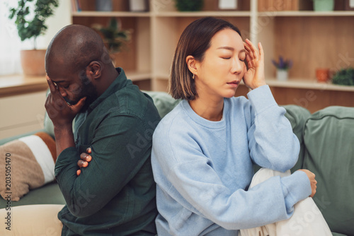 Quadro em tela Multiracial adult couple sitting back to back on couch in their apartment