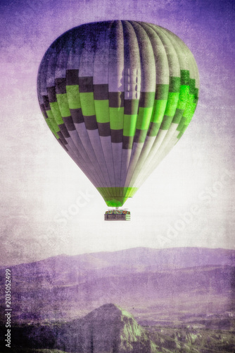 Cappadocia, Turkey, Europe: graphic reworking in pastel purple and fluorescent green of traditional hot air balloons floating in the sky over the valley of Cavusin in the region in Central Anatolia 